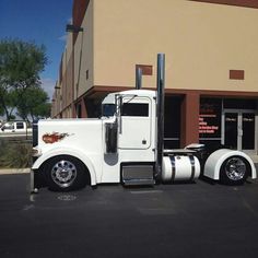 a white semi truck parked in front of a building