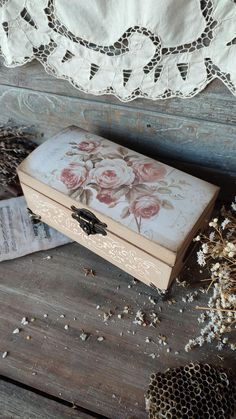 an old wooden box sitting on top of a table next to dried flowers and lace