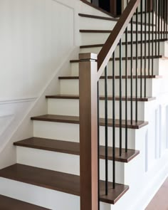 a staircase with wooden handrails and white walls