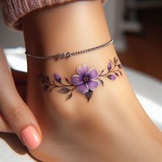 a woman's foot with purple flowers and leaves on the ankle bracelet tattoo design