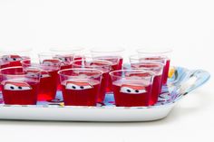 glasses filled with red liquid sitting on top of a blue and white tray topped with cartoon characters