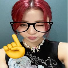 a woman with red hair and glasses holding up a peace sign