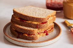 a stack of four sandwiches sitting on top of a plate next to a jar of jelly