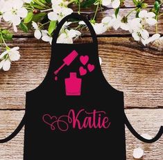 a black apron that says rachel with pink scissors and hair dryer in front of flowers