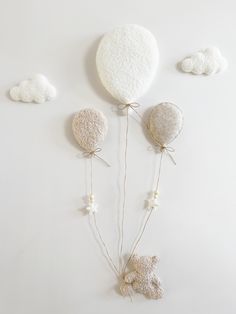 three white balloons are attached to string and tied with twine, on a white background