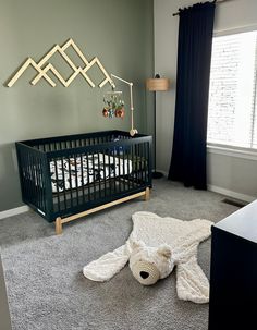 a baby's room with a crib, rug and teddy bear on the floor