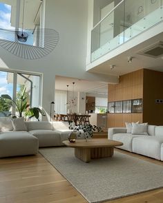 a living room filled with white furniture and lots of glass doors leading to an open floor plan