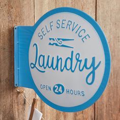 a blue and white sign that says self service laundry open 24 hours on the side of a wooden fence