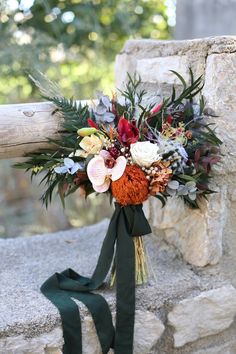 a bridal bouquet is tied to a stone wall