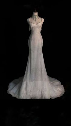 the back of a wedding dress on display in front of a black background with lights