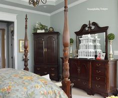 a bed room with a neatly made bed and a tall wooden dresser next to it