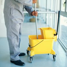 a man is cleaning the floor with a yellow mop and bucket in front of him