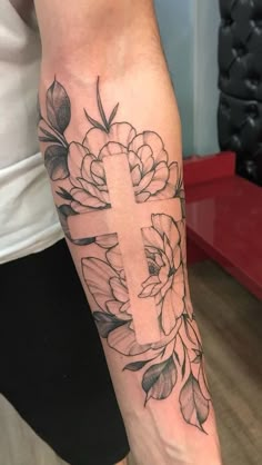 a woman's arm with flowers and a cross on it