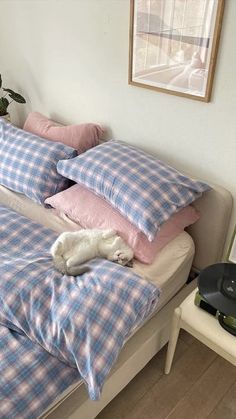 a bed with pink and blue pillows on top of it next to a potted plant