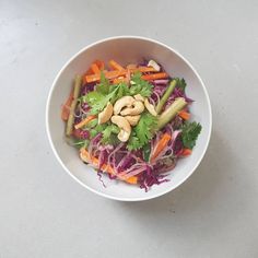 a white bowl filled with carrots, celery and cashew sprouts