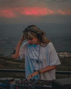 a woman with headphones on standing in front of a dj set