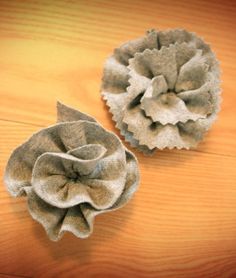 two fabric flowers sitting on top of a wooden table