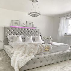 a white bedroom with a large bed and chandelier