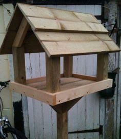 a wooden bird house sitting on top of a table next to a bike parked in front of a building