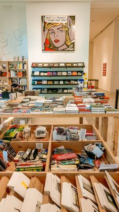 a room filled with lots of books on top of wooden shelves next to a painting