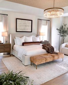 a bedroom with a large bed and chandelier hanging from it's ceiling