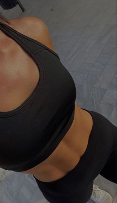 a woman in black sports bra top and leggings holding a cell phone up to her ear