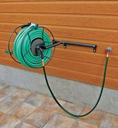 a green hose connected to a wall mounted air conditioner on the side of a building