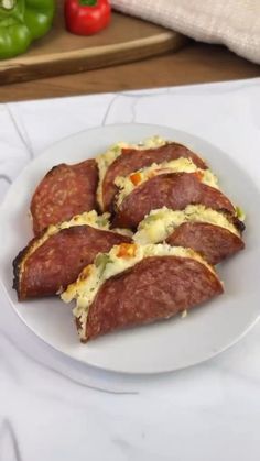 four slices of sausage on a plate with cheese and peppers in the backgroud