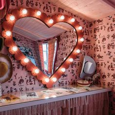 a heart shaped mirror sitting on top of a counter in front of a wallpapered wall