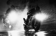 two motorcyclists in the rain at night on their bikes with headlights shining