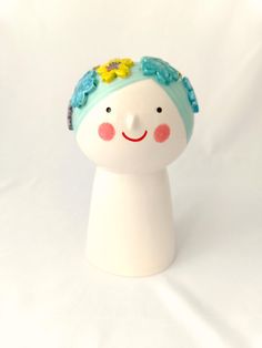 a white ceramic figurine with blue hair and flowers on it's head