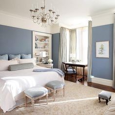 a bedroom with blue walls and white bedding, chandelier hanging from the ceiling