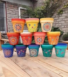 a group of colorful flower pots sitting on top of a wooden table