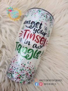 the tumbler is decorated with colorful confetti and sparkles, which says get your tinsel in a mug