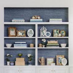 a white bookcase filled with lots of books next to a vase and other items