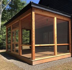 a small wooden structure sitting on top of a grass covered field next to a forest