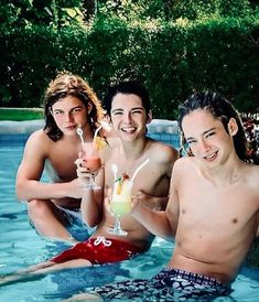 three people are sitting in the pool drinking cocktails and having fun with each other