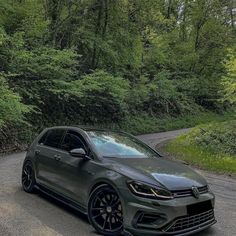 a grey volkswagen golf gtr parked on the side of a road in front of some trees