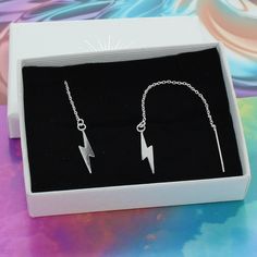 A unique pair of on trend sterling silver chain threader earrings with delicate lightning bolts suspended at the ends. The beautiful sterling silver lightning bolt earrings would make a great gift for any friend or loved one of any age. The threads are a nice length making a great statement accessory to your outfit. Each pair of earrings arrives in a striking White gift box with a contrasting silver logo. A free gift wrapping service is available upon request. Dimensions 10cm length making a 5cm Elegant Nickel-free Metal Threader Earrings, Elegant Adjustable Nickel-free Threader Earrings, Modern Nickel-free Sterling Silver Threader Earrings, Lighting Bolt Earrings, Lightning Bolt Earrings Dangle, Chain Threader Earrings, Lightning Bolt Earrings, Silver Logo, Threader Earrings