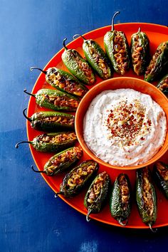 an orange plate topped with stuffed peppers and dip