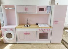 a pink play kitchen with sink, oven and microwave