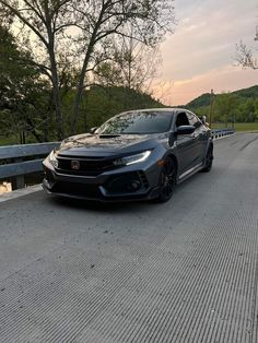 a black car parked on the side of a road next to some trees and water