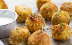 some fried food on a wooden table next to a small bowl of ranch dressing and dipping sauce