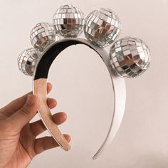 a hand holding up a mirror with disco balls on it and a wooden stick sticking out of it