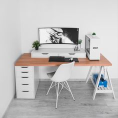 a desk with a computer, keyboard and mouse on it in front of a white wall