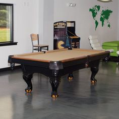 a pool table in a room with chairs and a map on the wall behind it