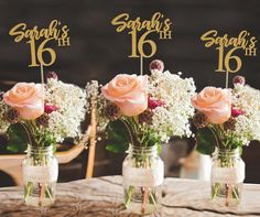 three mason jars filled with pink roses and baby's breath on top of a wooden table