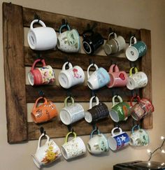 there is a wooden rack with cups hanging from it's sides on the wall