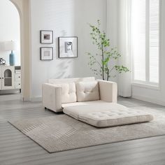 a living room with a white couch and rug on the floor, framed pictures on the wall