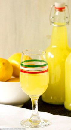 a glass filled with yellow liquid next to some lemons